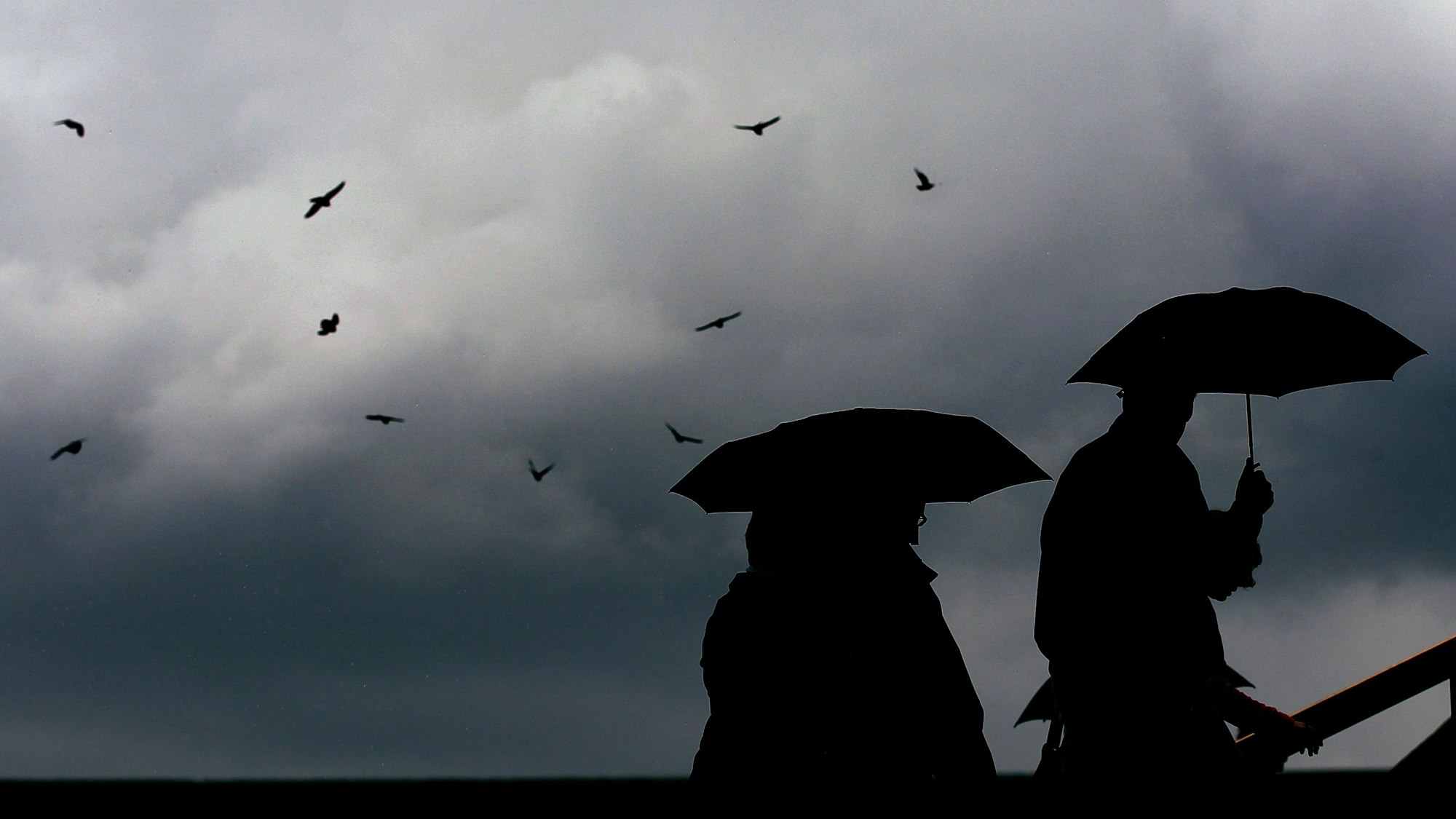 ARCHIV - 23.06.2011, Nordrhein-Westfalen, Köln: Passanten gehen mit Regenschirmen durch eine Stadt. (zu dpa: «Regen und Wolken zum Ende der Woche in Hessen») Foto: Oliver Berg/dpa +++ dpa-Bildfunk +++