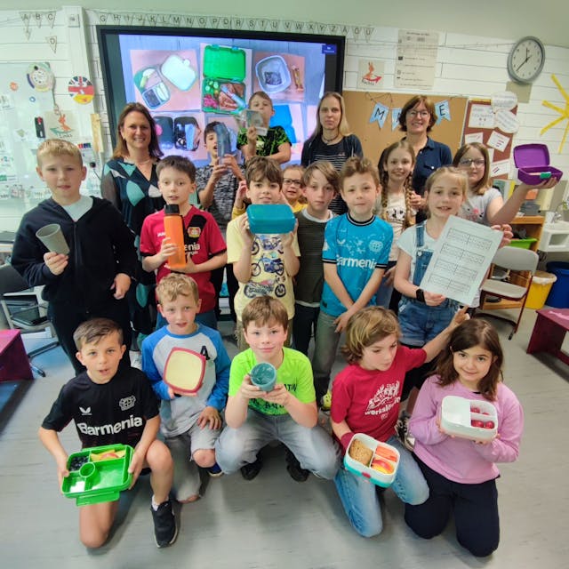 Eine Schulklasse posiert mit Brotdosen für ein Foto.