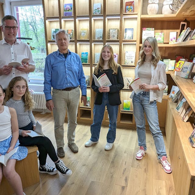 Bürgermeister Norbert Crump (l.), Organisator Jochen Starke und vier Preisträgerinnen des Vorjahres vor Regalen, in denen sich verschiedene Bücher befinden.