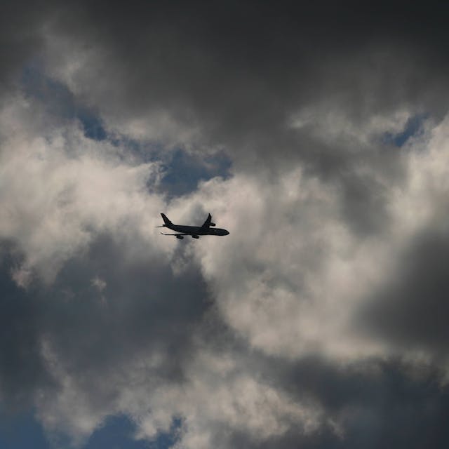 Ein Flugzeug fliegt inmitten eines Unwetters am Himmel in mehrere Gewitterwolken hinein. (Symbolbild)