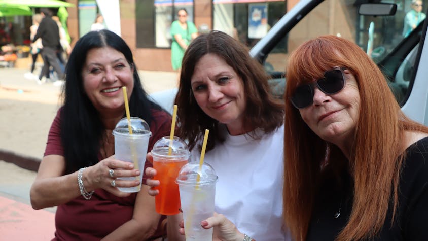 Zu sehen sind drei Besucherinnen, die einen Cocktail trinken.