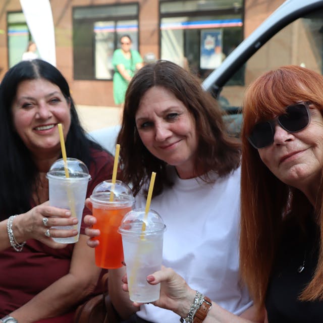 Zu sehen sind drei Besucherinnen, die einen Cocktail trinken.