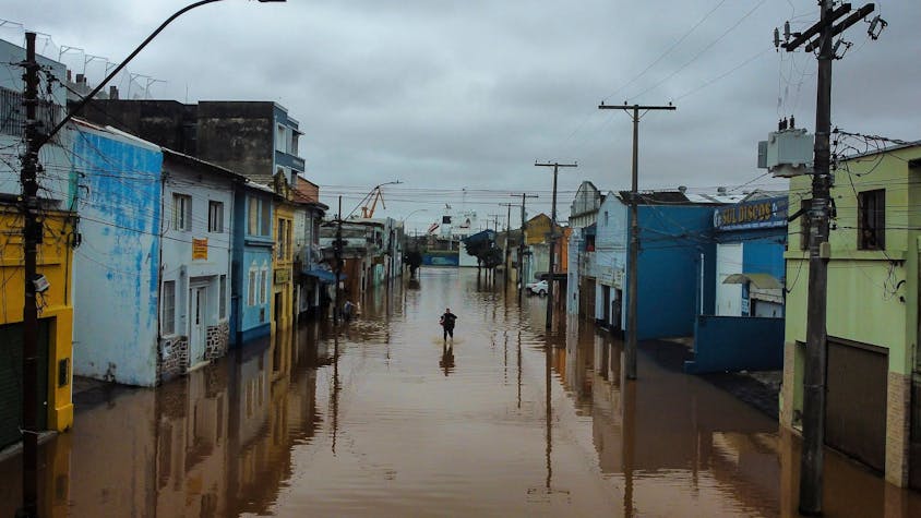 dpatopbilder - 03.05.2024, Brasilien, Porto Alegre: Ein Mann watet in Porto Alegre im brasilianischen Bundesstaat Rio Grande do Sul durch ein von schweren Regenfällen überschwemmtes Gebiet. Foto: Carlos Macedo/AP/dpa +++ dpa-Bildfunk +++