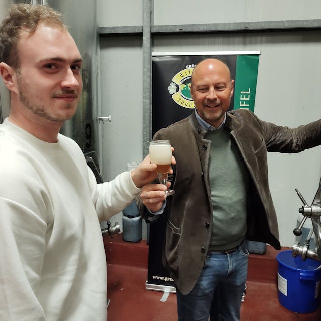 Johannes Schweizer reicht einem Besucher ein gezapftes Bier.
