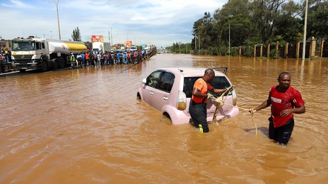 Das von der chinesischen Staatsagentur Xinhua verbreitete Bild zeigt Menschen, die im Hochwasser ein Auto ziehen.
