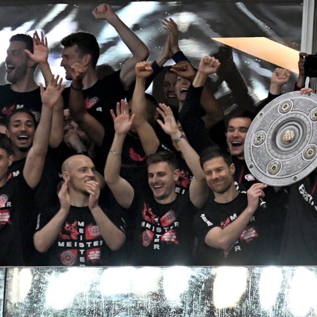 Die Leverkusener Mannschaft um Trainer Xabi Alonso jubelt mit einer stilisierten Meisterschale von der Tribüne ins Stadion
