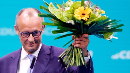 Friedrich Merz, CDU-Bundesvorsitzender, hält seinen Blumenstrauss nach der Wahl zum Bundesvorsitzenden beim CDU-Bundesparteitag hoch.