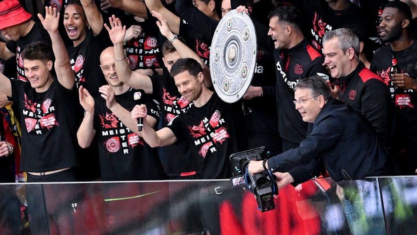 Die Leverkusener Mannschaft um Trainer Xabi Alonso jubelt mit einer stilisierten Meisterschale von der Tribüne ins Stadion.