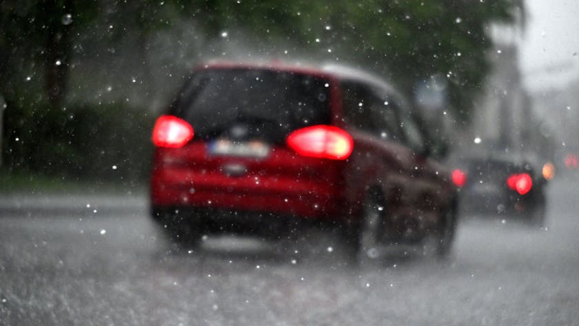 Ein Auto fährt durch einen Hagelschauer. Der DWD warnt vor Starkregen in Köln und der Region. (Symbolbild)