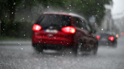 Ein Auto fährt durch einen Hagelschauer. Der DWD warnt vor Starkregen in Köln und der Region. (Symbolbild)