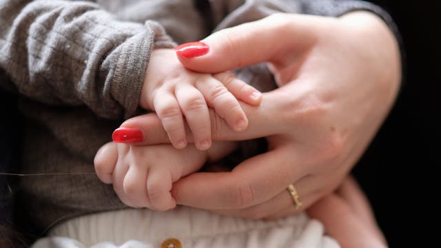 Eine Frau hält ein zwei Monate altes Baby im Arm.