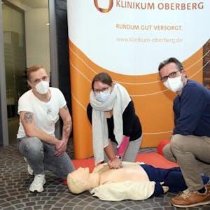 Pfleger Martin Robbins (l.) und Dr. Jörg Niehüser-Saran zeigen Vanessa Tröder, wie die Herzdruckmassage funktioniert.
