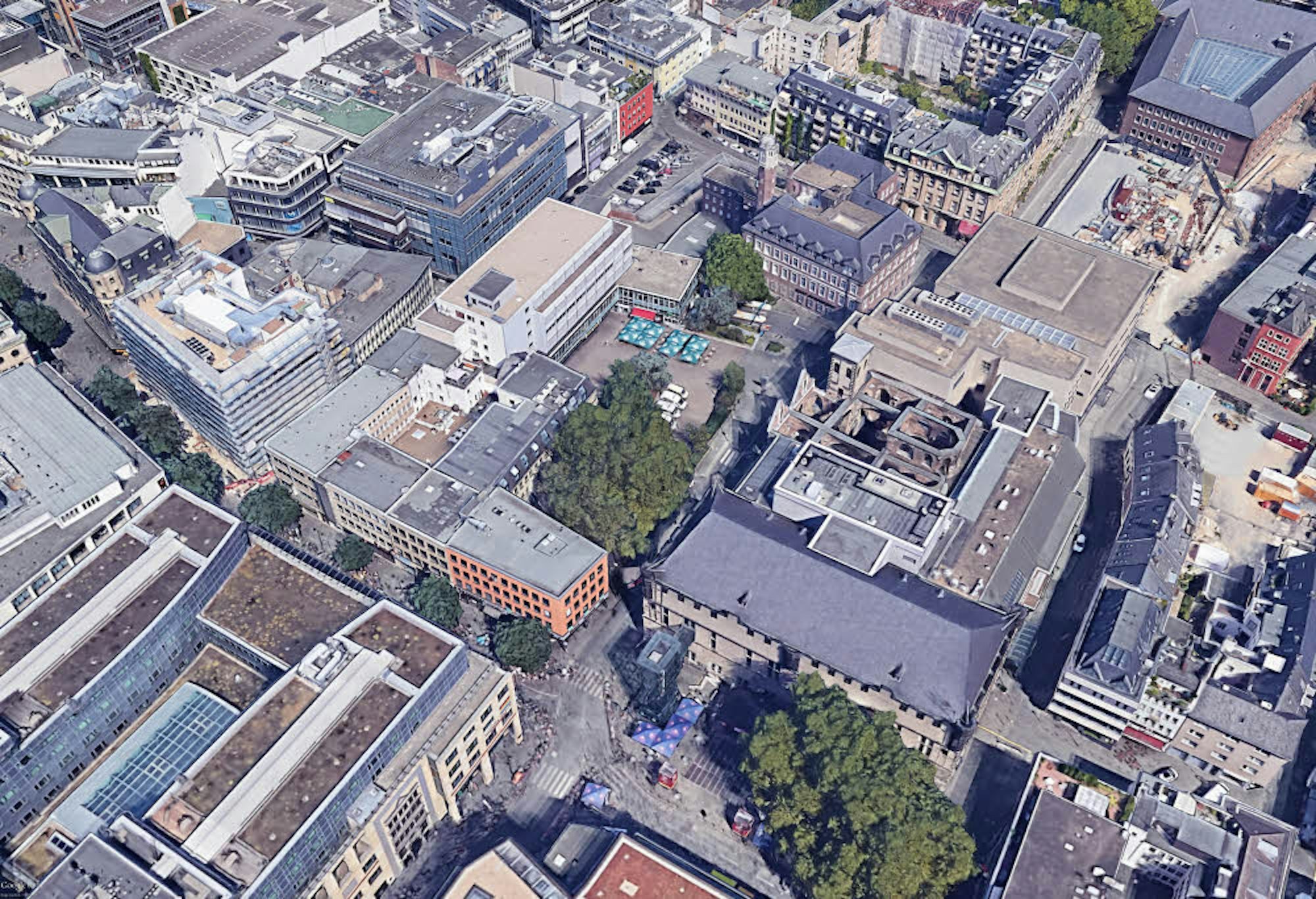 Der Quatermarkt (Bäume in der Mitte), auf dem der Neubau entstehen soll. Das benachbarte Haus Neuerburg, ebenfalls am Platz, soll freigestellt werden. Vorne ist der Gürzenich zu sehen (Gebäude an den Bäumen vorne).
