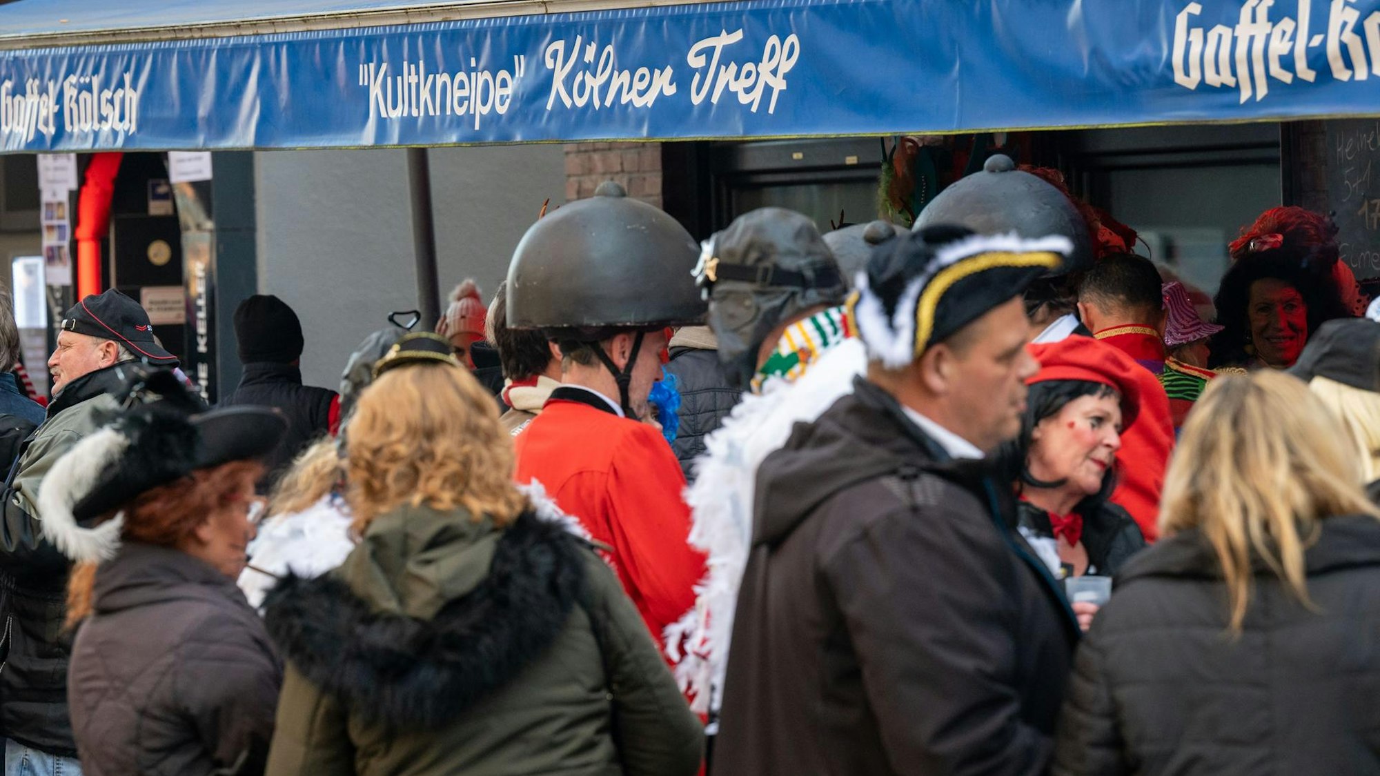 Kostümierte Menschen stehen vor der Kneipe „Kölner Treff".