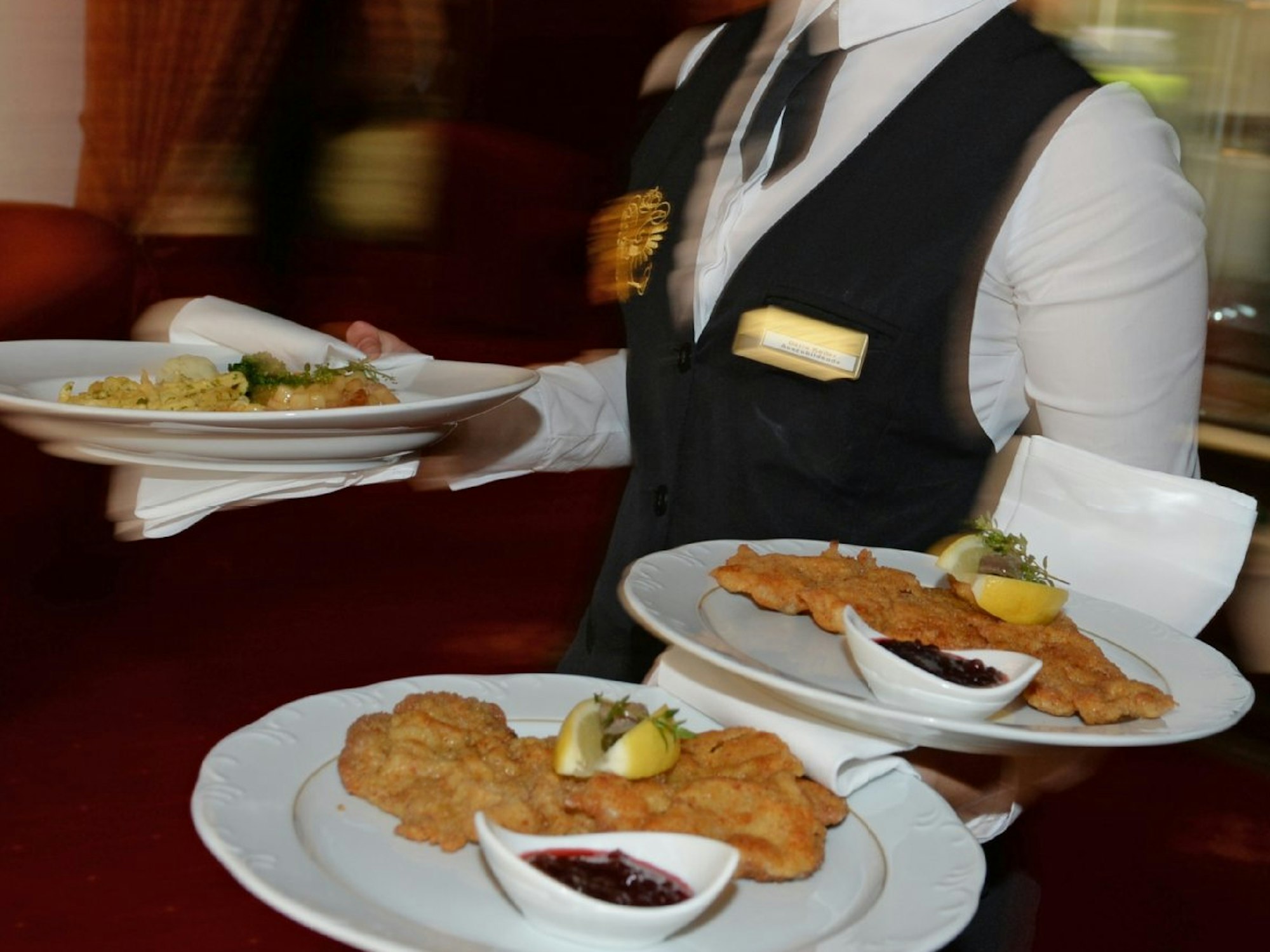 Ein Kellner serviert in einem Restaurant mehrere Teller.