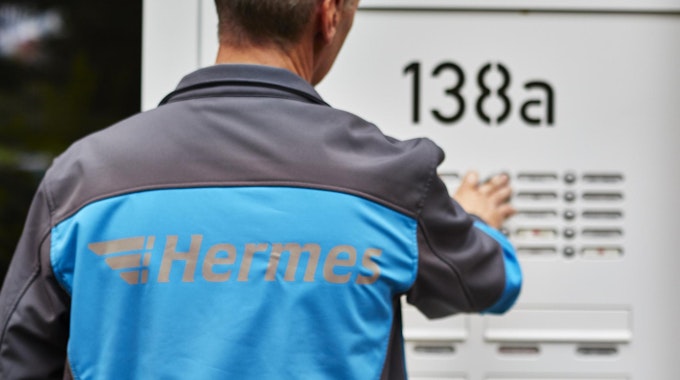Ein Hermes-Mitarbeiter klingelt an einer Haustüre.