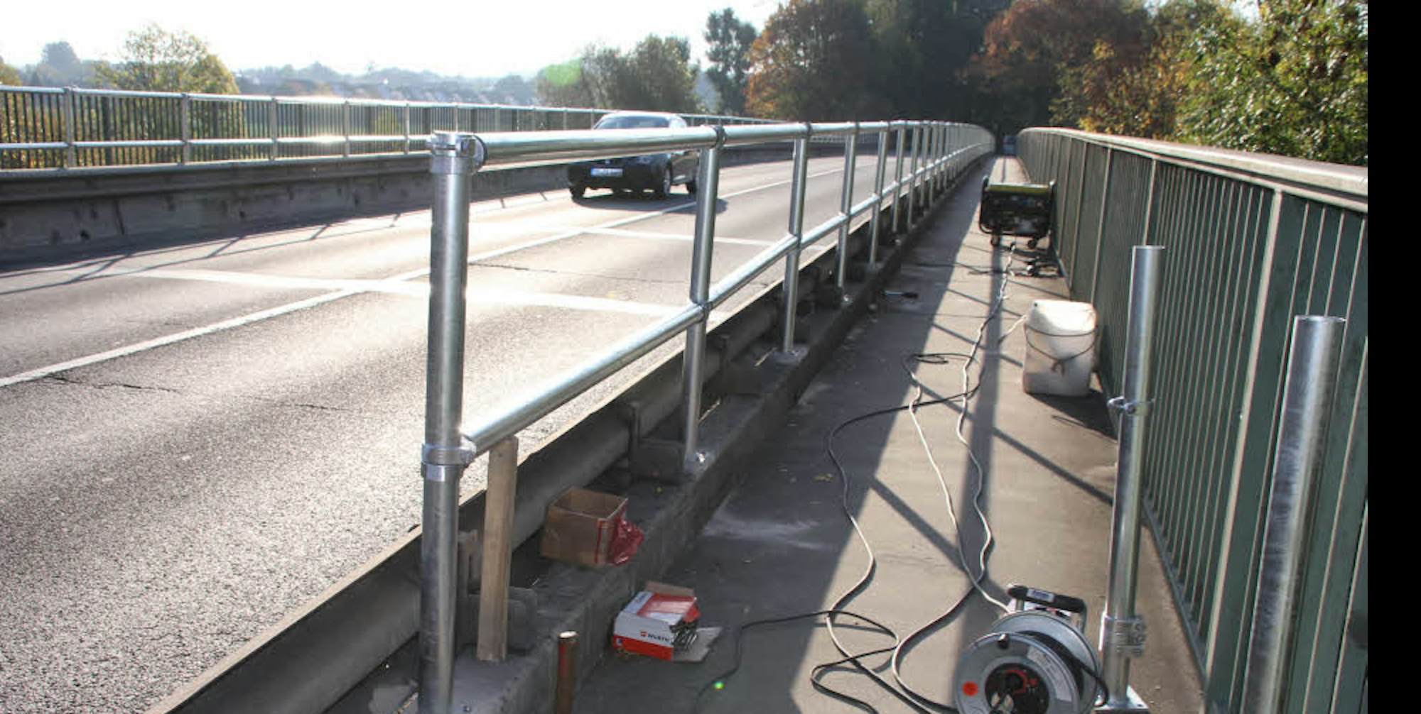 Auf die niedrige Mauer entlang der Fahrbahn auf der Allner Brücke wurde ein zusätzliches Geländer montiert, das Radfahrer und Fußgänger schützen soll.