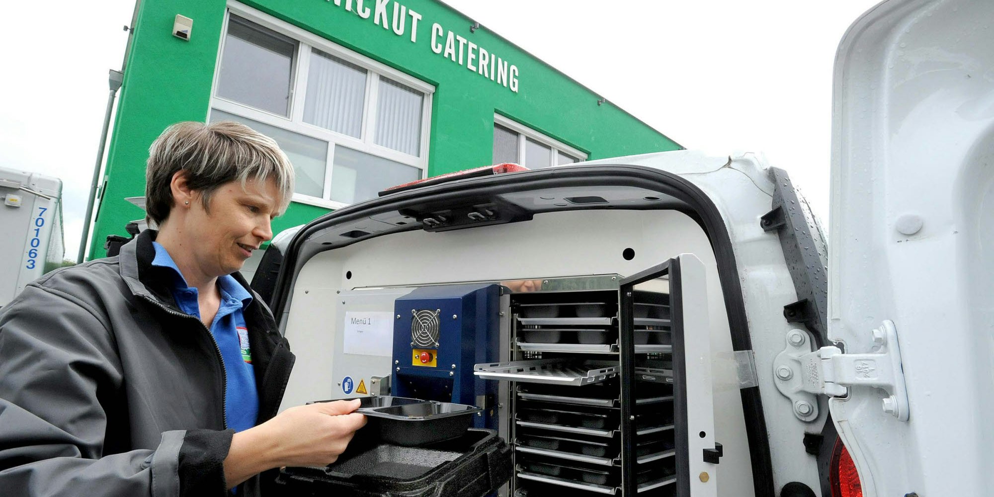 Claudia Graff, Mitarbeiterin des Burscheider Catering-Unternehmens, am neuen Fahrzeug mit eingebautem Ofen.