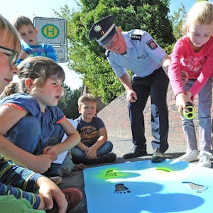 Hauptkommissar Ulrich Schramm zeigte den Kindern, wie die Markierungen mit Schablone und Sprühdose gelingen.