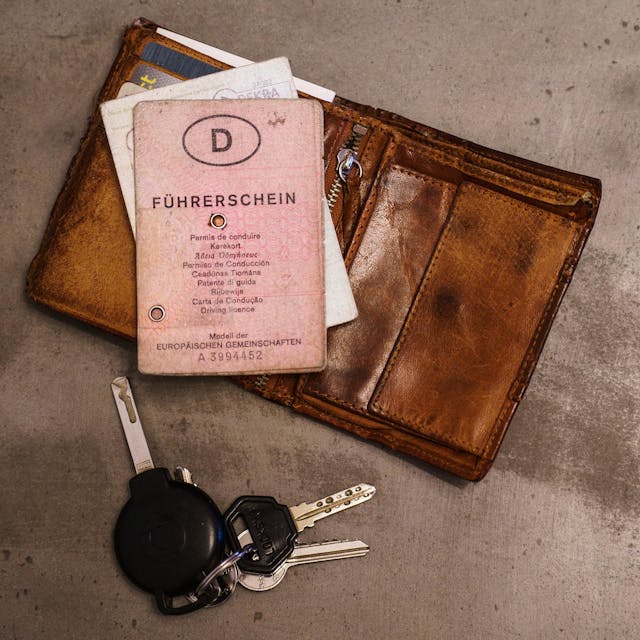 Das Foto zeigt einen rosa Führerschein, ein Portemonnaie und einen Schlüsselbund