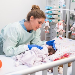 Eine Kinderkrankenpflegerin versorgt ein Neugeborenes.