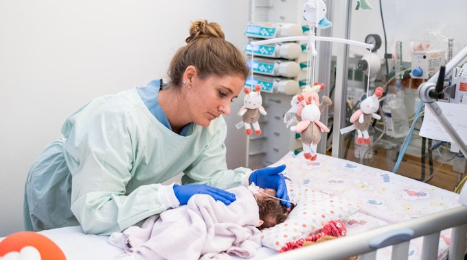 Eine Kinderkrankenpflegerin versorgt ein Neugeborenes. 