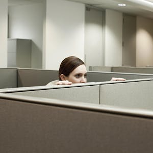 Eine Frau schaut in einem Büro über eine Trennwand.