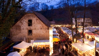 Weihnachtsmarktstände und bunte Lichter vor Burganlage