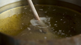Ein Holzstäbchen steckt in sprudelnd kochendem Öl.