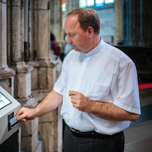 Domdechant Robert Kleine zückt die Geldkarte und ist damit der erste Spender am digitalen Opferstock im Dom.