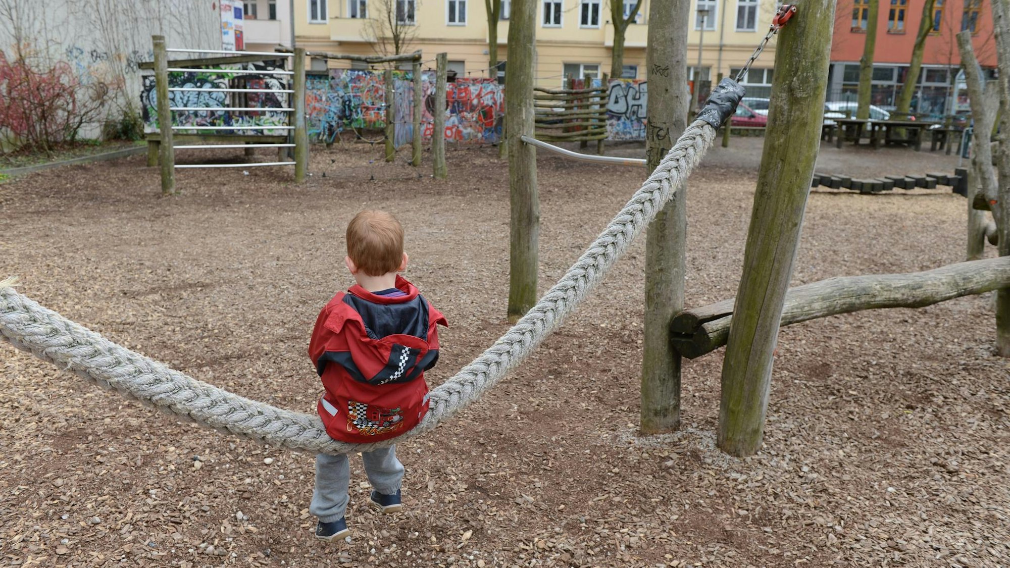 Ein Kind sitzt alleine auf dem Spielplatz.