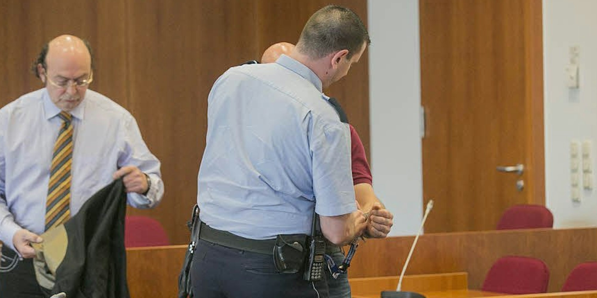 Der Angeklagte (verdeckt) betritt den Gerichtssaal. Sein Verteidiger Uwe Krechel (links) sagt, an der Selbstbezichtigung sei nichts wahr.