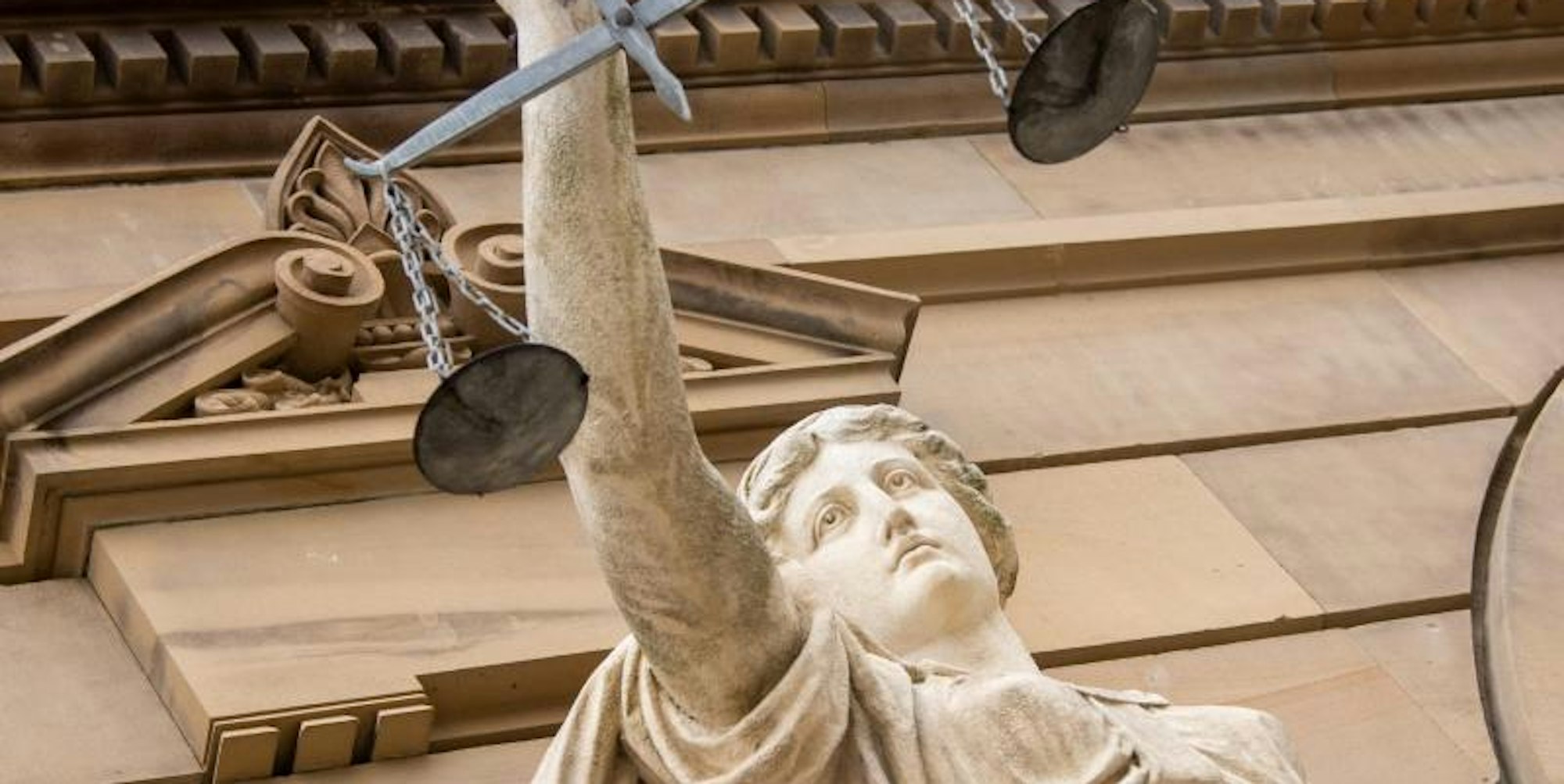 Vor dem Landgericht hält eine Statue der Justitia eine Waagschale.