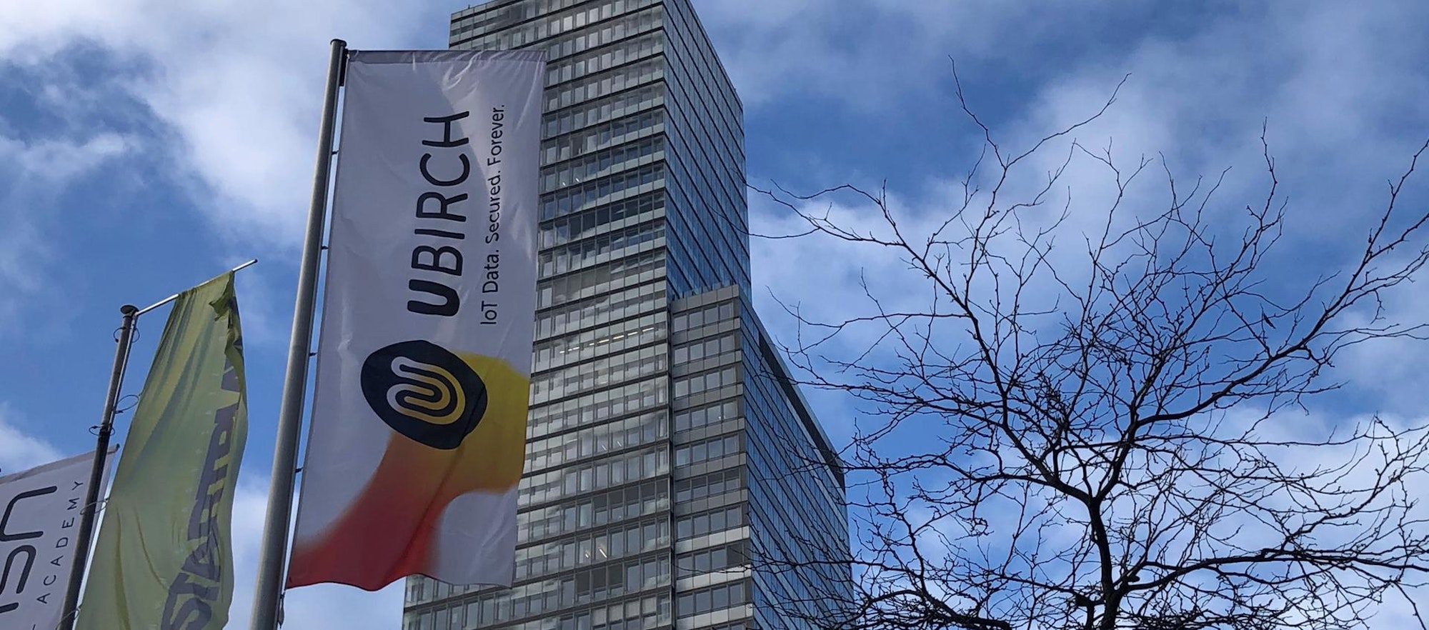 Vor dem KölnTurm im MediaPark weht eine Fahne mit der Aufschrift Ubirch.