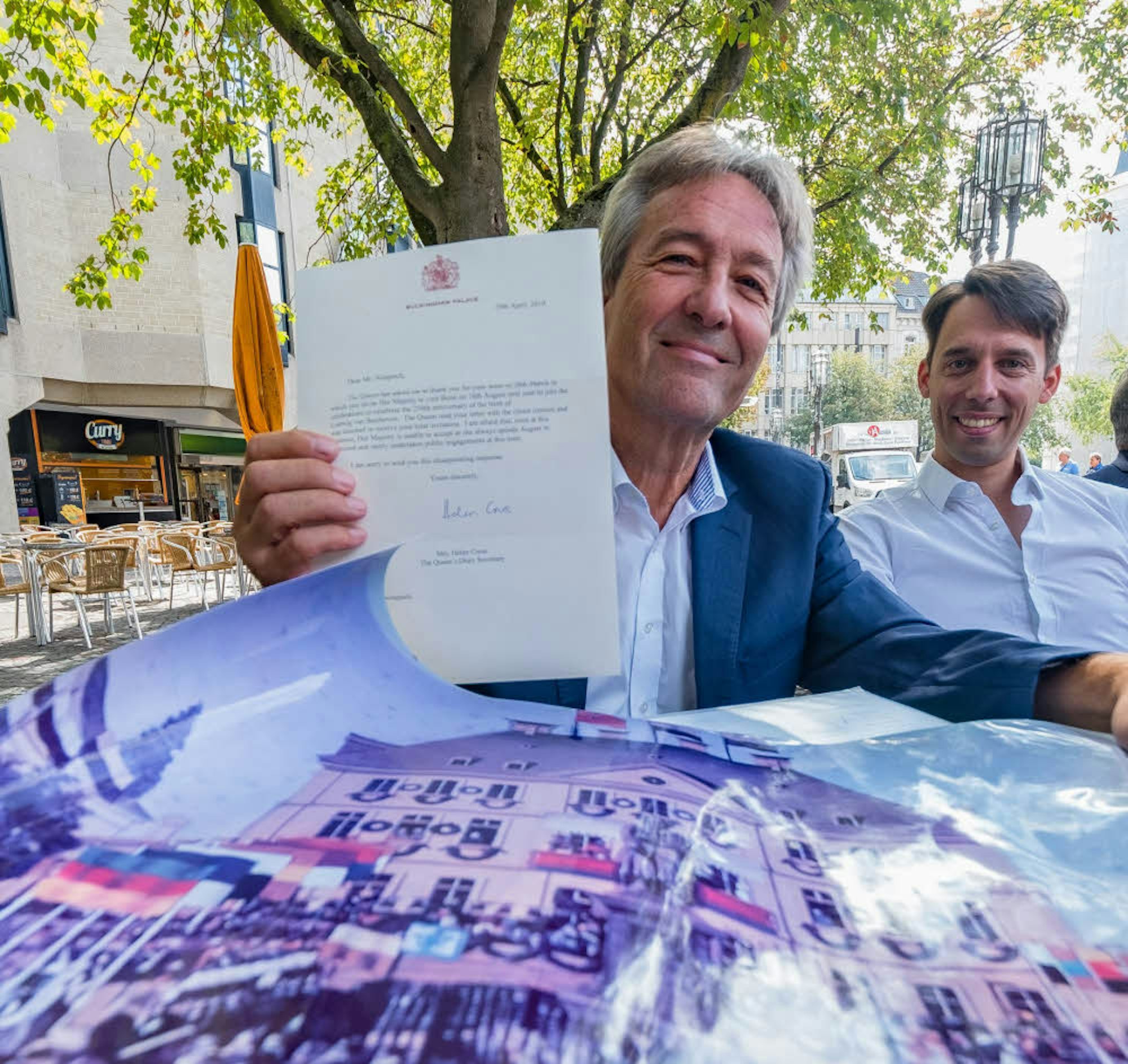 Ex-Oberbürgermeister Jürgen Nimptsch, rechts Regisseur Lajosch Wenzel, zeigt das Originalschreiben des Buckingham-Palastes.