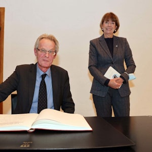 Vor den Augen von Oberbürgermeisterin Henriette Reker trägt sich Stefan Sommer ins Gästebuch ein.