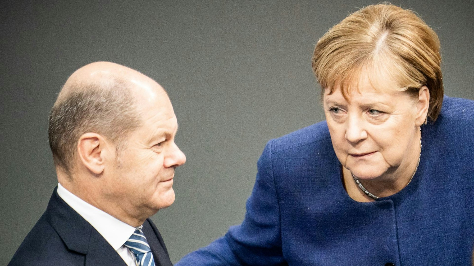 Olaf Scholz und Angela Merkel schauen sich an.