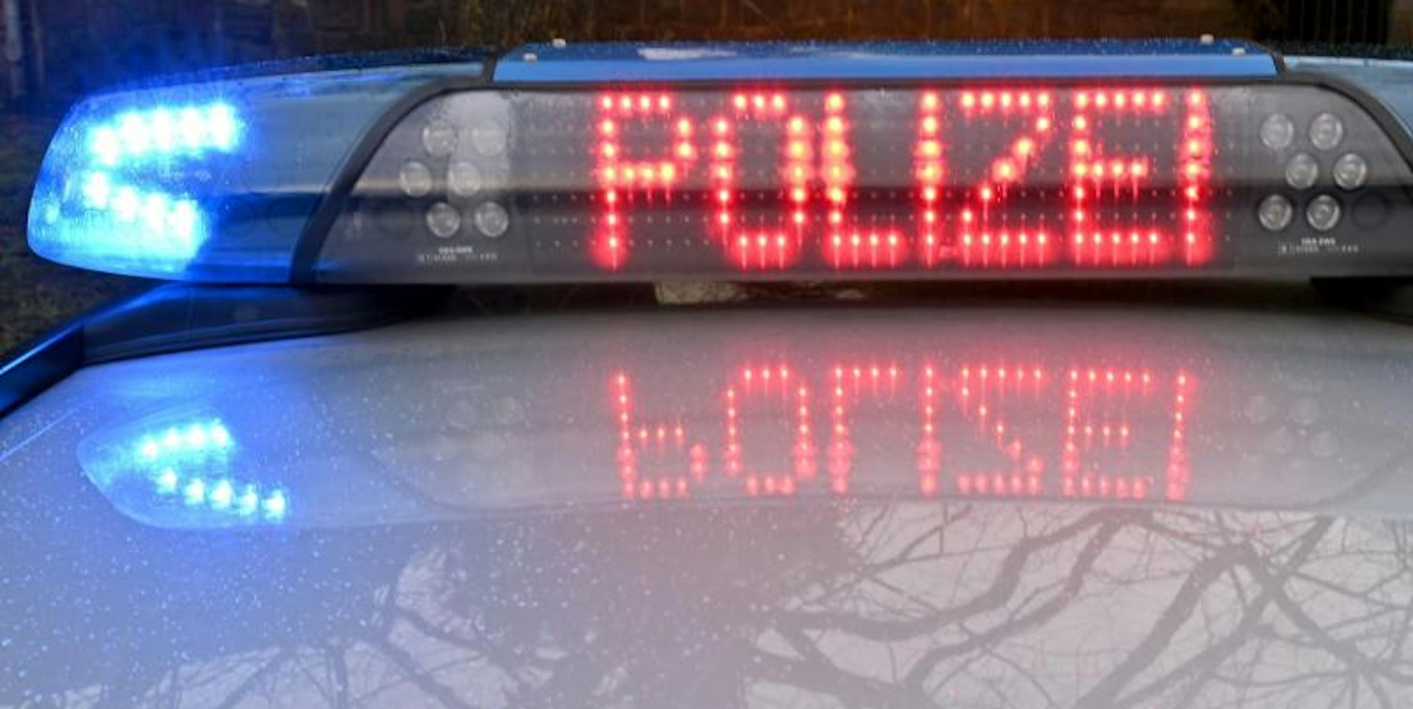 Die Schriftzug „Polizei” leuchtet auf dem Dach eines Streifenwagens der Polizei.