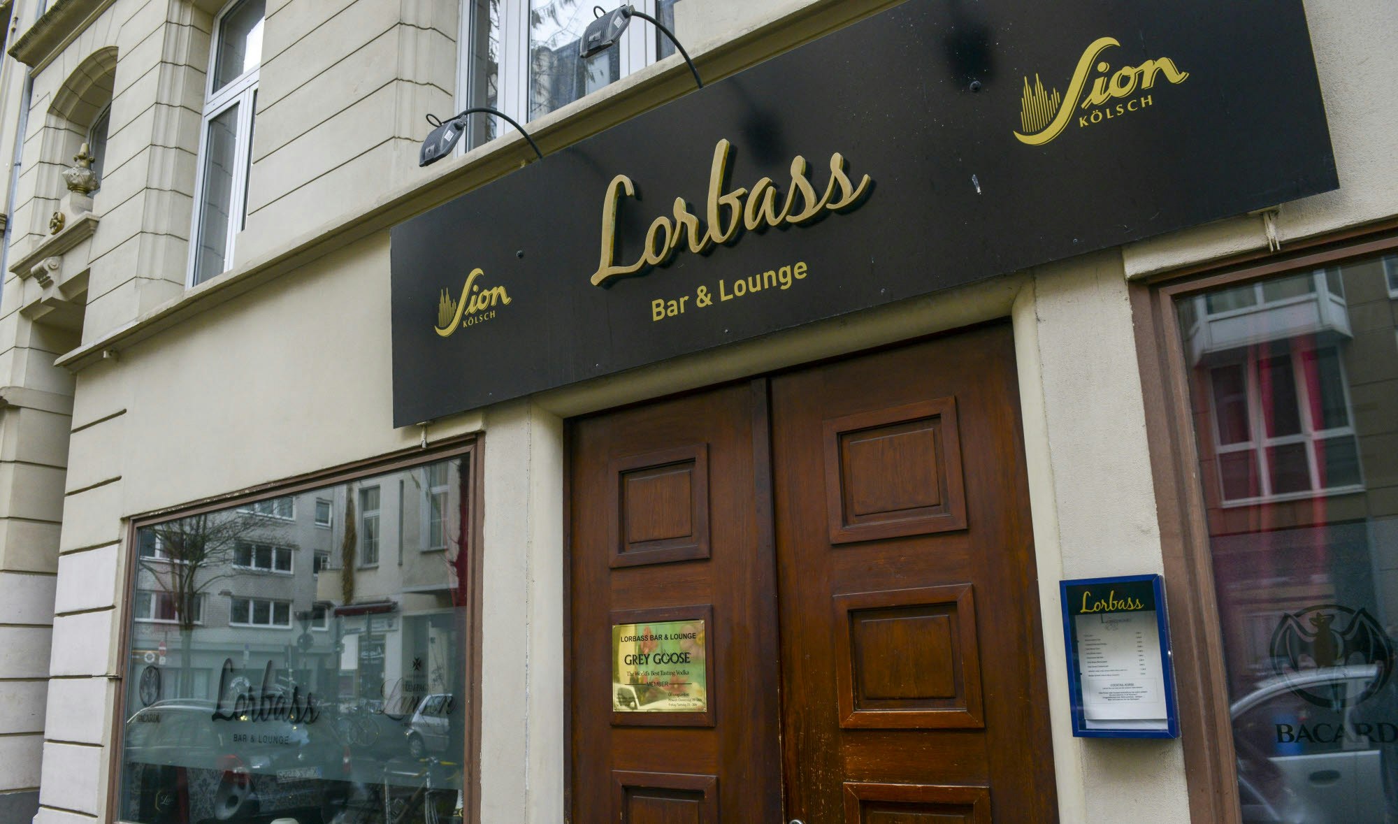 Eine Fassade mit großer Eingangstür aus Holz, darüber das Logo goldene Logo von Lorbass auf schwarzer Tafel.