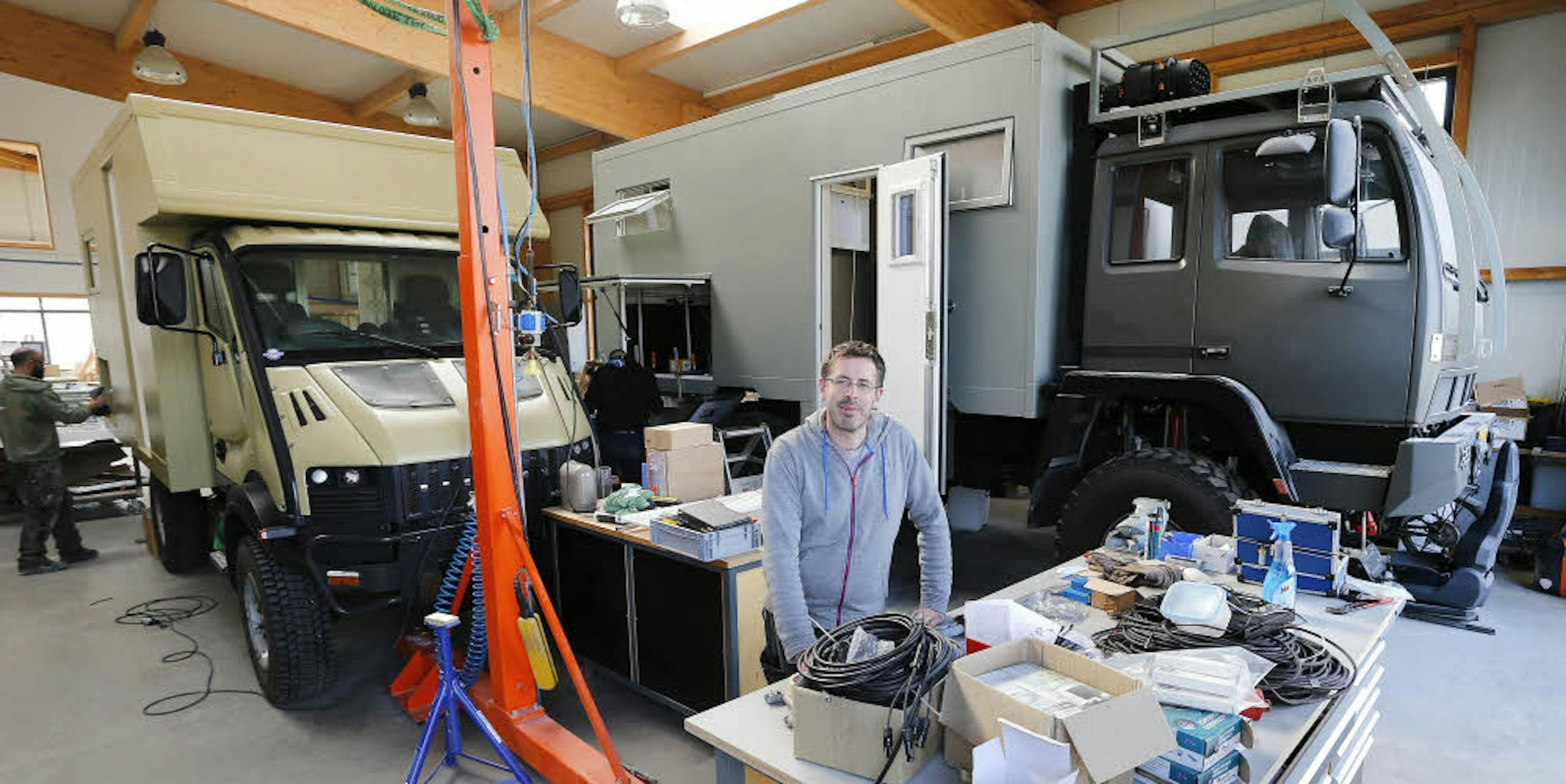 Stephan Schmidt setht in seiner Firma „Orangework“, hinter ihm ein Steyr- (rechts) und ein Bremach-Wohnmobil.