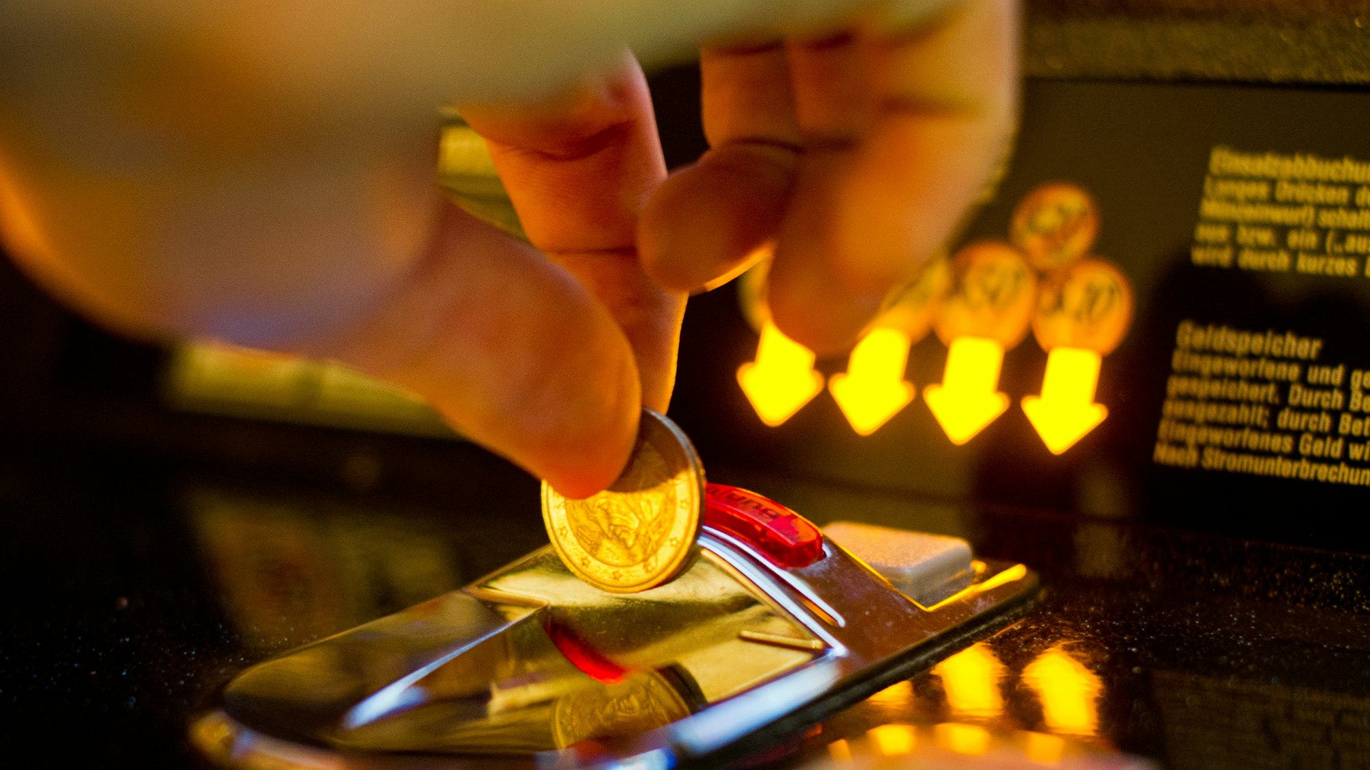 Das Bild zeigt den Einwurf einer Geldmünze in einen Spielautomaten