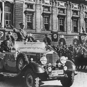 Adolf Hitler grüßt die ihm zujubelnde Menschenmenge in Wien, neben ihm sitzt der österreichische Kanzler Arthur Seyss-Inquart. 