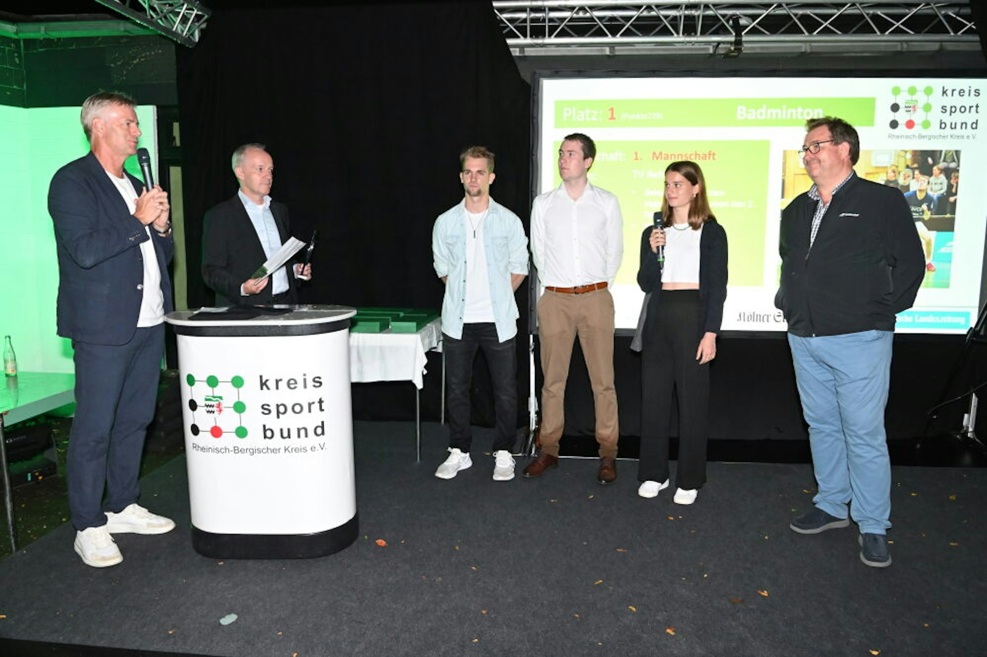 Christian Bonnen (2.v.l.) betonte bei der Freiluft-Ehrung 2021 die Bedeutung der Kreissparkasse für die Region. Mit Tom Bartels ehrte er das Badmintonteam TV Refrath.