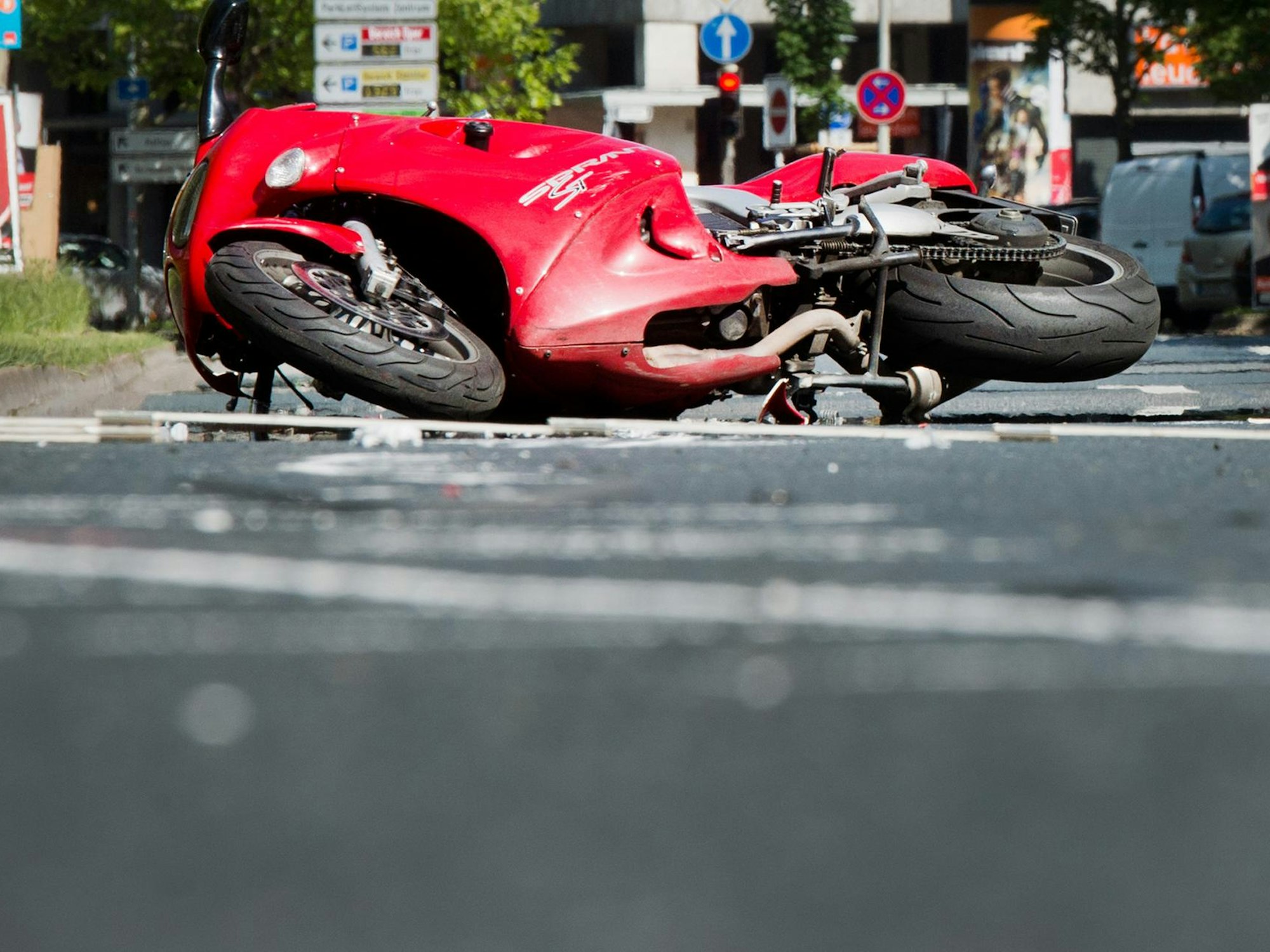 Köln. Ein rotes Motorrad liegt nach einem Unfall auf dem Boden.