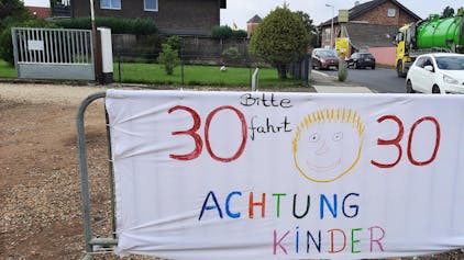 Mit bunten Bannern werden die Autofahrer in Friesheim gebeten, Tempo 30 zu fahren.