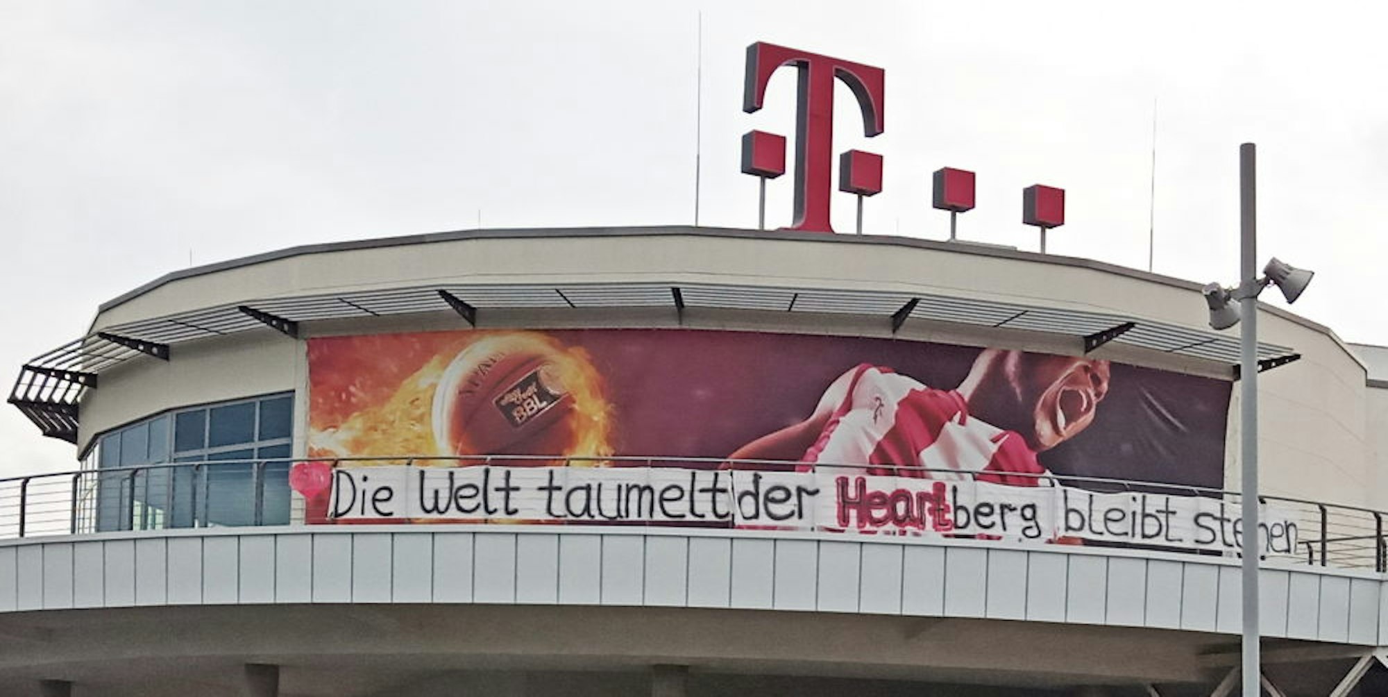 Ein Banner des Baskets-Fanclubs am Telekom Dome soll Optimismus verbreiten: „Die Welt taumelt, der Heartberg bleibt stehen.“