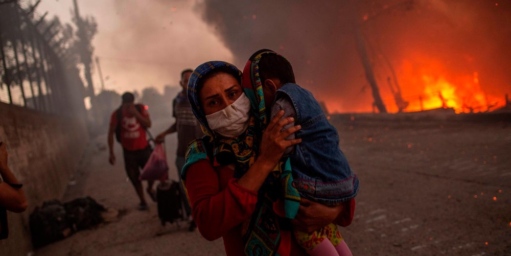 Frau flieht mit Kind vor Feuer im Flüchtlingslager Moria