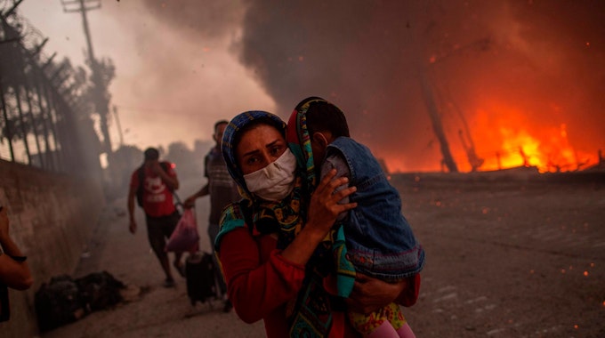 Frau flieht mit Kind vor Feuer im Flüchtlingslager Moria