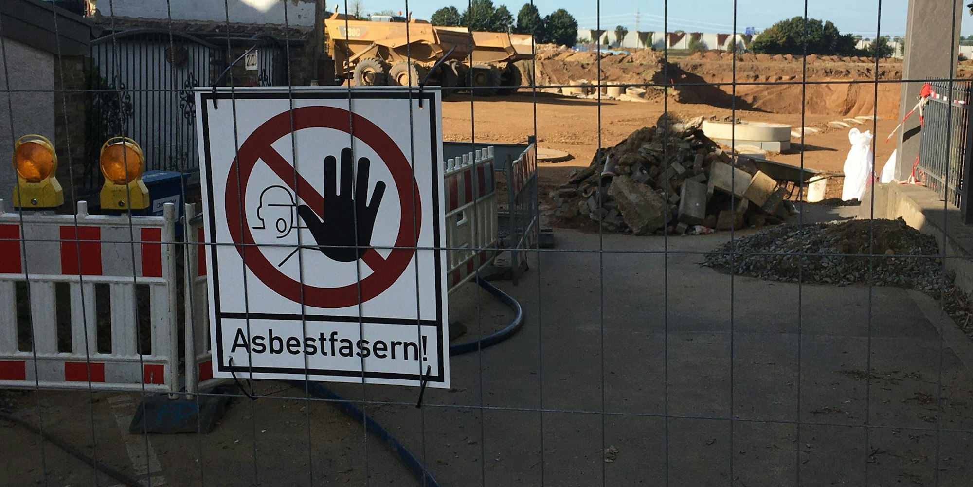 Schilder an den Absperrungen warnen vor Asbest. 