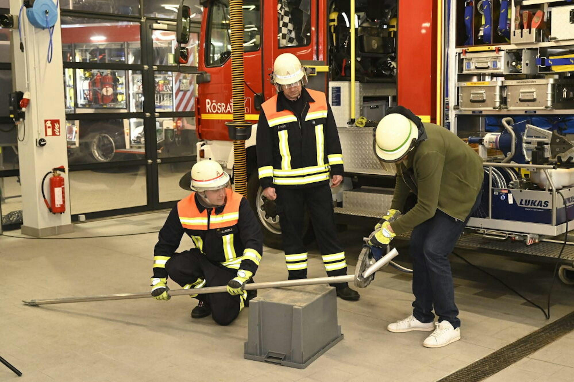 Das Feuerwehrhaus als Studio: Fernsehreporter Matthias Fiedler lässt sich Fahrzeuge und Material der Feuerwehr im und vor dem Feuerwehrhaus in Forsbach erklären, packt selbst mit an und trennt mit der hydraulischen Schere eine Metallstange durch.